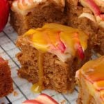 Slices of apple spice cake with caramel drizzle and apple slices on top, close-up on a cooling rack