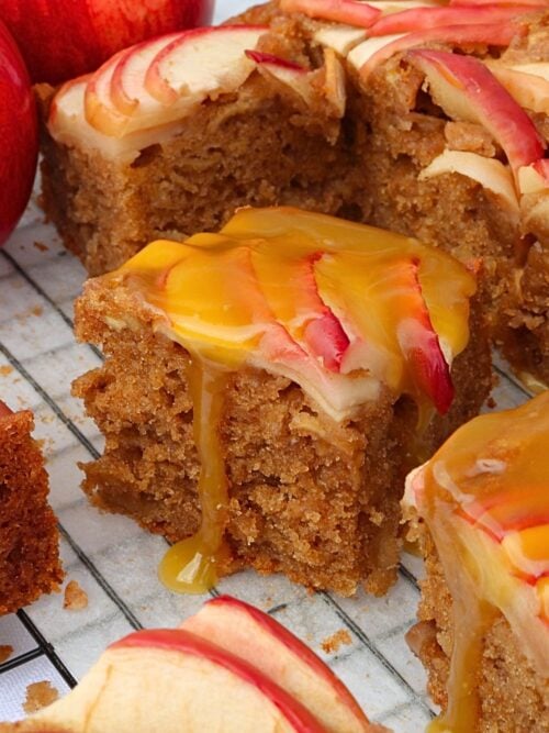Slices of apple spice cake with caramel drizzle and apple slices on top, close-up on a cooling rack