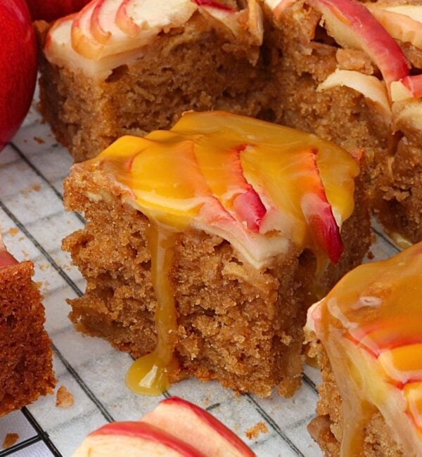 Slices of apple spice cake with caramel drizzle and apple slices on top, close-up on a cooling rack