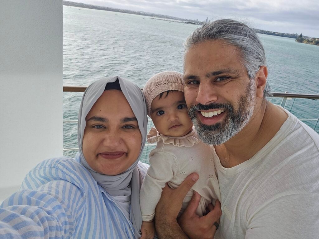 Smiling family selfie on a boat with the ocean behind them and a distant shoreline.