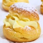 Stack of cream puffs filled with vanilla cream, lightly dusted with powdered sugar.