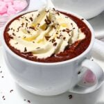 Chocolate mug dessert topped with whipped cream and chocolate shavings in a white mug