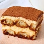Slice of tiramisu with mascarpone cream and coffee-soaked sponge, topped with cocoa powder