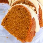 Slices of carrot cake with cream cheese frosting on a plate, close-up view showing moist interior and orange crumb edge.