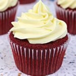 Red velvet cupcake with pale yellow buttercream frosting swirled on top in a paper liner