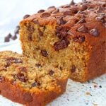 Slice of banana bread studded with chocolate chips, showing a moist, chunky interior and a few chips on top.