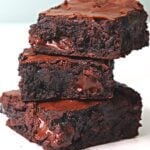 Stack of rich, fudgy chocolate brownies with melted chocolate centers on a white surface
