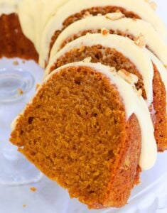 Slices of pumpkin cake with cream cheese frosting and almond pieces on top, arranged on a plate